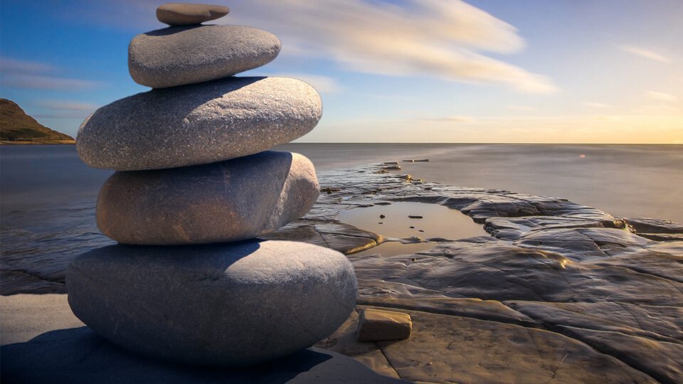 A stack of rocks on the beach near water.