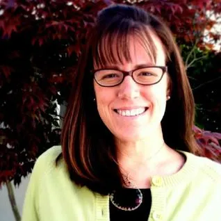 A woman with glasses and brown hair wearing a yellow jacket.